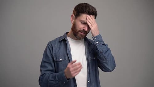 Man Rubs Eyes and Forehead in Distress