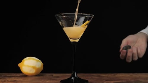 Bartender Pouring Cocktail into Martini Glass with Lemon