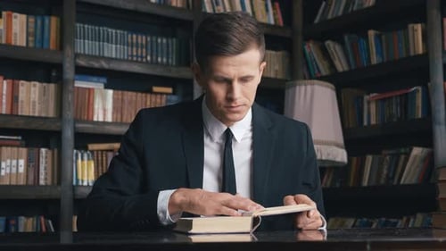Geschäftsmann im Klassisch Anzug sitzt in der Bibliothek und liest Buch