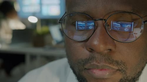 Closeup Portrait of Serious Businessman in Dark Office Working Wearing Glasses Looking at Monitor