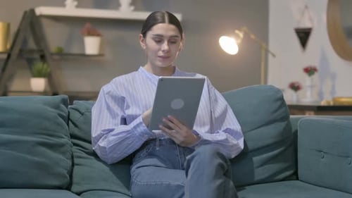 Woman Using Tablet on Teal Couch at Home