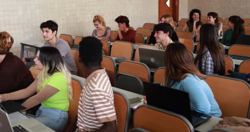 Multiracial students working with laptop computers inside classroom at school university