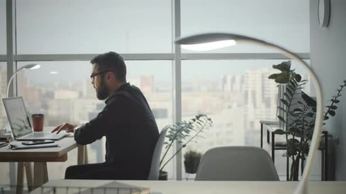 Young Businessman Using Laptop in Modern Office