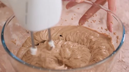 Electric Mixer Blending Chocolate Cream in Glass Bowl
