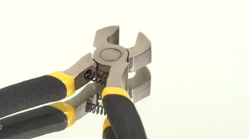 Parte de cortadores de fio com cabo amarelo e cinza em branco, reflexão, rotação