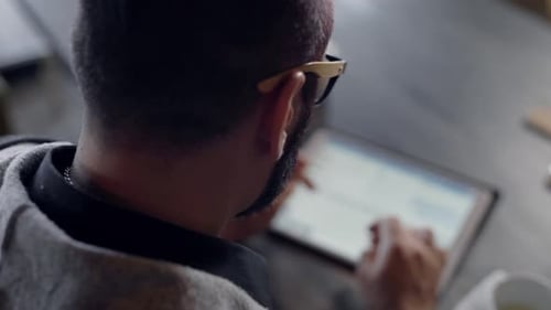 Erwachsener Mann arbeitet mit Tablet über drahtloses Internet, durchsucht Websites und tippt auf dem Touchscreen