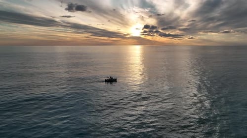 Fishing boat far out to sea at sunset