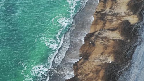 Luftdrohne aus türkisblauen Meereswellen, die am Sandstrand brechen, von oben nach unten Ansicht von Mustern und Be