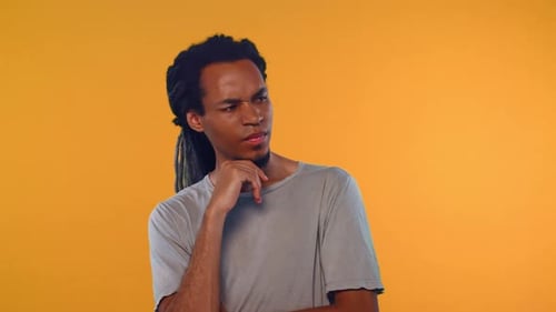 Thoughtful Young Man Posing Against Orange Background