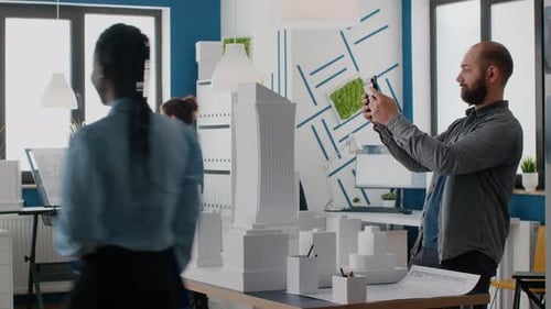 Mann-Architekt arbeitet mit Tablet, um den Bauplan am Gebäudemodell zu planen