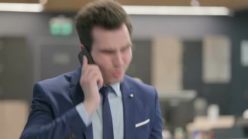 Young Adult Businessman Talking on a Phone in Office
