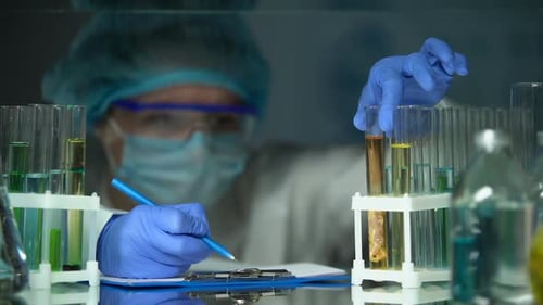 Assistant de laboratoire analysant un échantillon de viande dans un agent de conservation et rédigeant les résultats