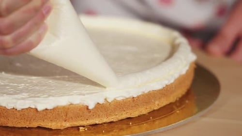 Cake Decorator Adds White Frosting to Cake