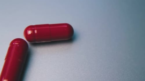 Motion Along Row of Red Medical Capsules on White Background