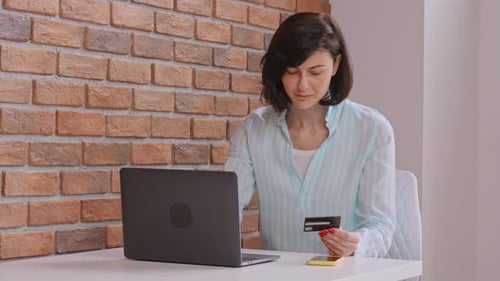 Woman Uses Credit Card for Online Purchase on Laptop