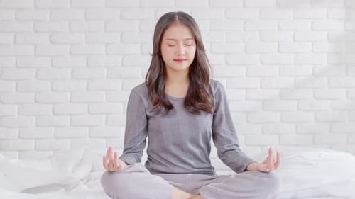 Woman Practices Calming Meditation on Bed Indoors