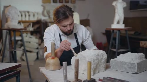 Sculpteur qui nettoie les restes de calcaire avec une brosse