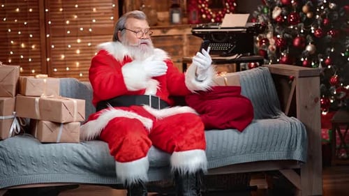 Santa Claus Video Chats on Phone Surrounded by Gifts