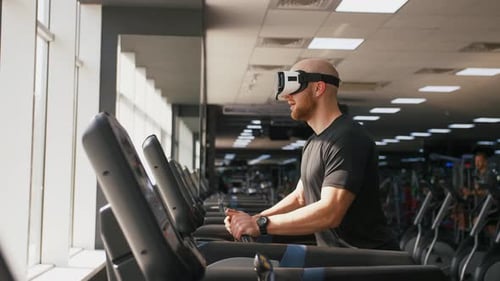 Young Strong Man Exercising on Treadmill at the Gym Wearing VR Glasses Slow Motion