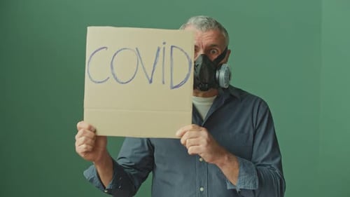Man Holds Cardboard Sign Wearing Protective Respirator Mask