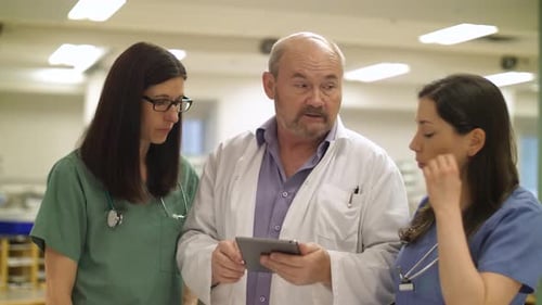 Medical Professionals Discussing Information on Tablet in Hospital