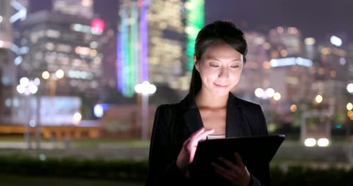 Woman Works On Tablet At Night In City