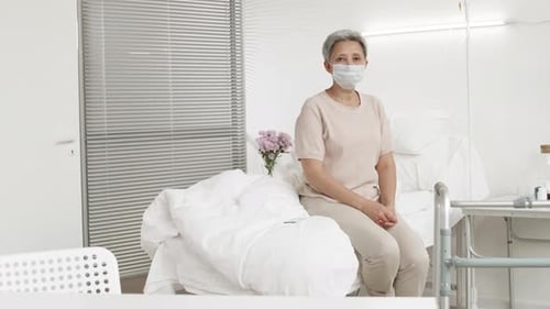 Aged Asian Woman Wearing Mask Sitting in Hospital