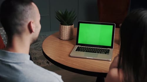 Young Man and Woman at Home Office Business Using Green Mock-up Screen Laptop Computer While Sitting