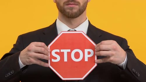 Male in Business Suit Holding Stop Sign