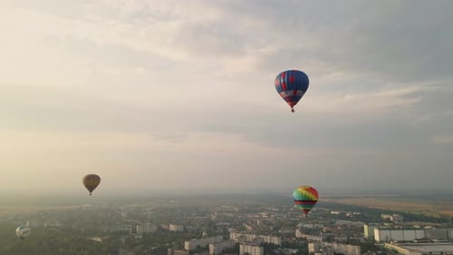 Colorful Hot Air Balloons Flying Over Buildings in Small European City at Summer Sunset, Aerial View