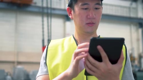 Young Asian Male Factory Worker Using a Digital Tablet