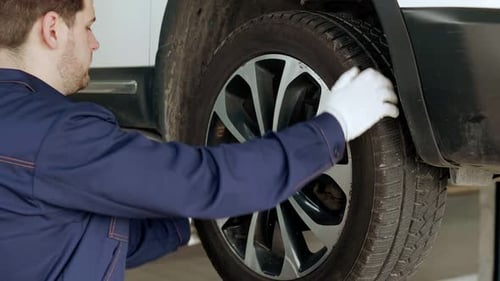 Auto Mechanic Checks a Wheel on a Car