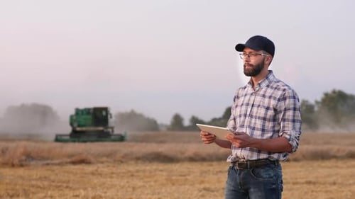 A Male Farmer Uses a Digital Tablet in the Field