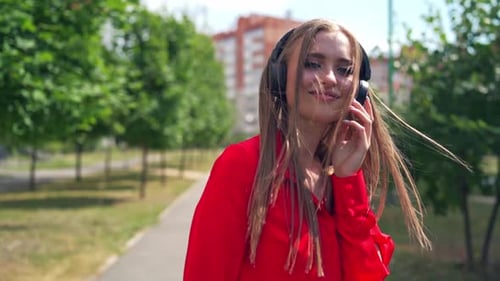 Smiling teenage girl with headphones outdoors.