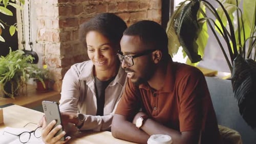 Happy Afro-American Couple Web Calling on Smartphone in Cafe