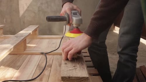 Sanding Wood Pallet with Power Tool Outdoors