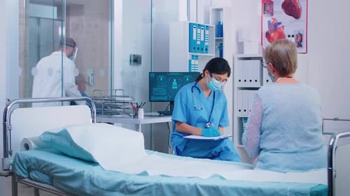 Doctor Consults with Senior Female Patient in Hospital