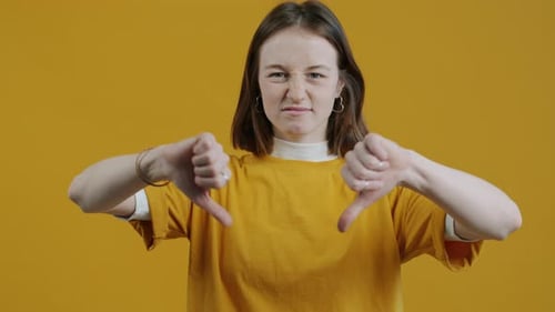 Slow Motion Portrait of Displeased Young Woman Gesturing Thumbsdown and Wrinkling Nose