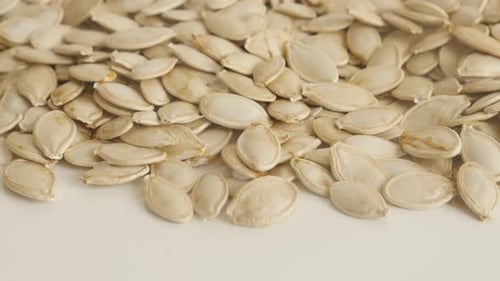 Raw pumpkin seed on white slow tilt 4K 2160p 30fps UltraHD footage - Pepitas on pile close-up 3840X2