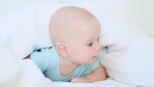 Infant Lies on Stomach on White Bed