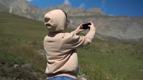 Woman Takes Pictures in Mountainous Landscape