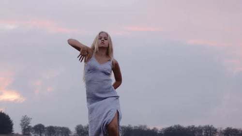 A Graceful Woman Dancer Dancing on a Field With Grey Skies