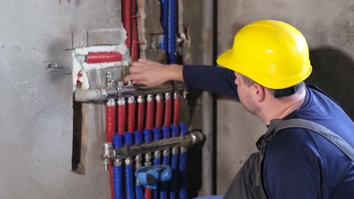 Construction Worker Adjusting Plumbing Pipes on Wall