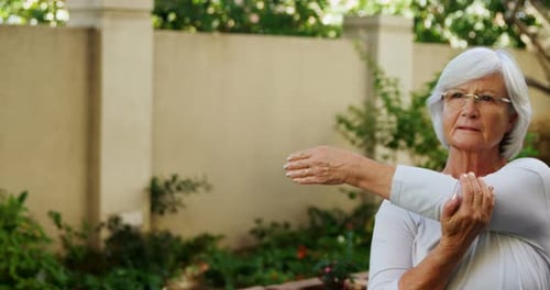 Senior woman with female trainer doing stretching exercise in garden 4k