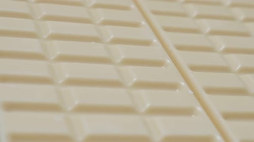 White milk chocolate blocks in the row slow tilt 4K 2160p 30fps UltraHD video - Tilting over shiny w