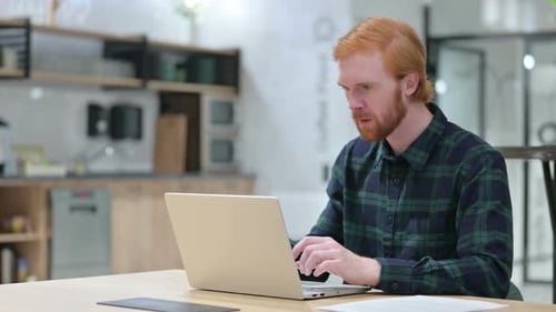 Red-Haired Man Celebrates Good News on Laptop