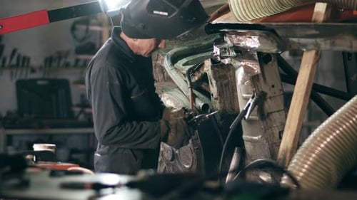 Un trabajador de una fábrica de soldadura está examinando una construcción metálica para soldar una pieza de metal sobre ella