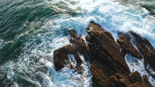 Ocean Waves Crash Against Stony Rocks During Sunrise on the Island of Sri Lanka. Aerial View.