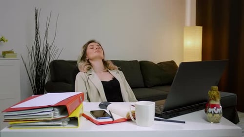 Woman Working At Desk Leans Back and Rests