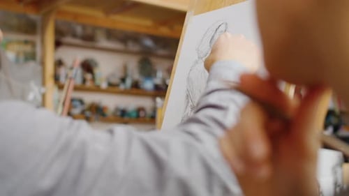 Close-up of Male Hand Drawing Picture with Pencil Working in Art Class Indoors